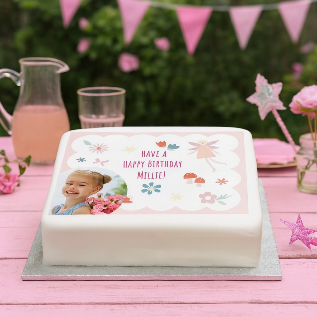 Birthday cake with a photo of a child and 'Happy Birthday Millie!' text on a pink tablecloth.