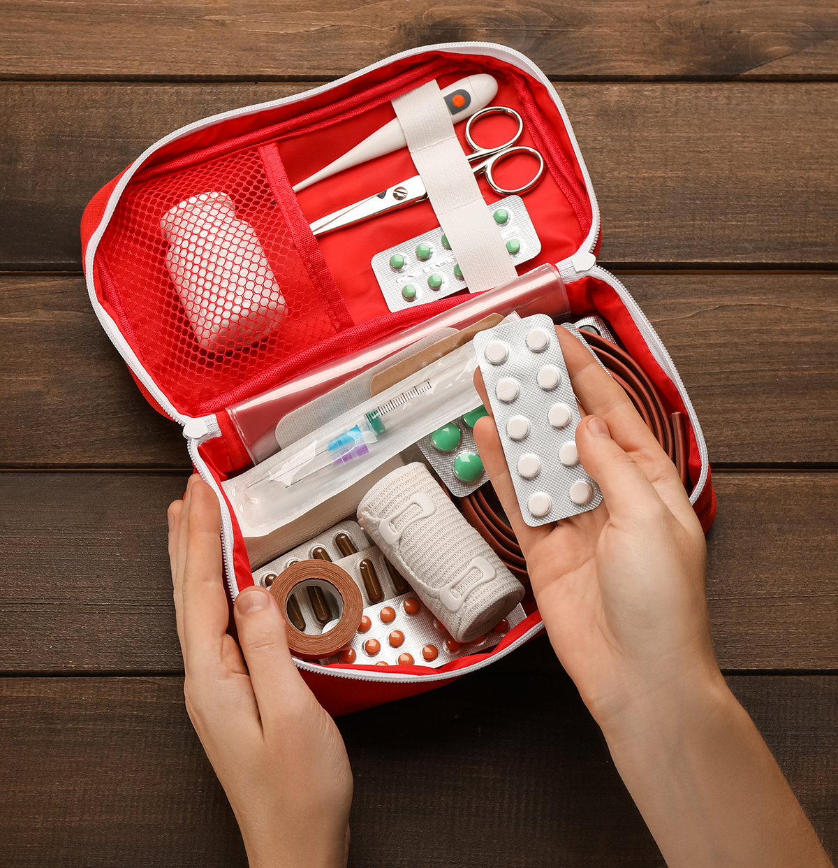 First aid kit with various supplies on a wooden surface