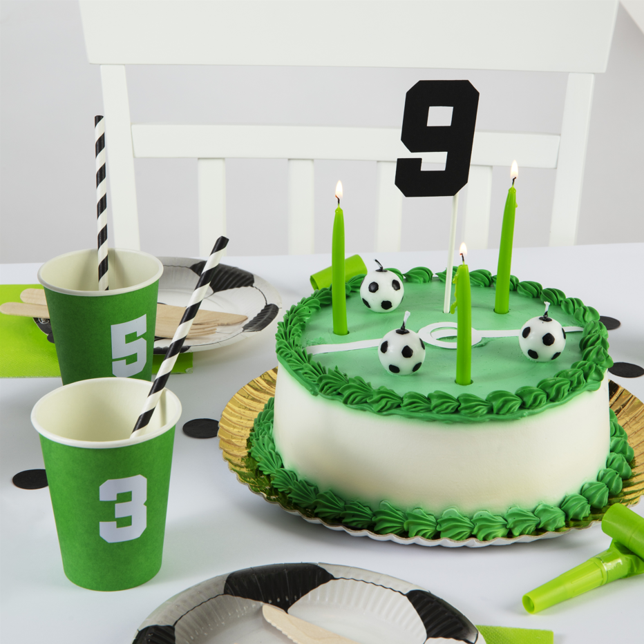 Birthday cake with soccer-themed decorations on a table with matching cups and plates.