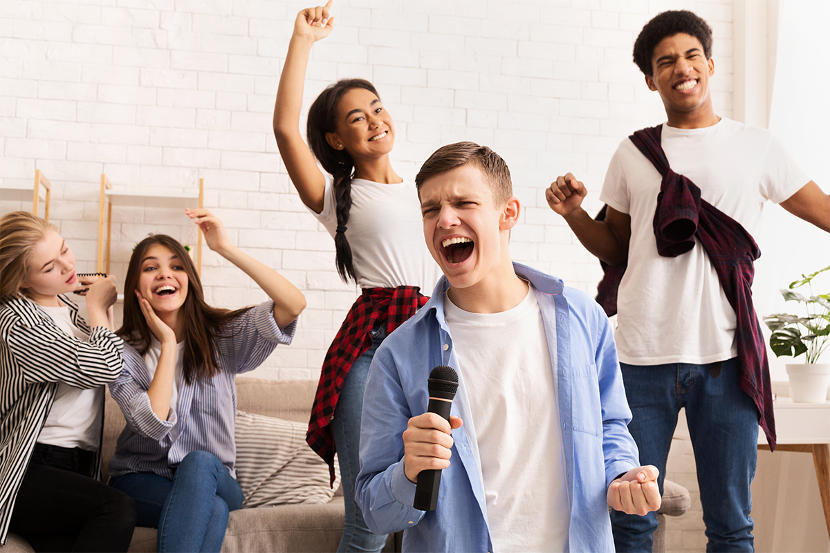 Group of young people singing together in a living room.