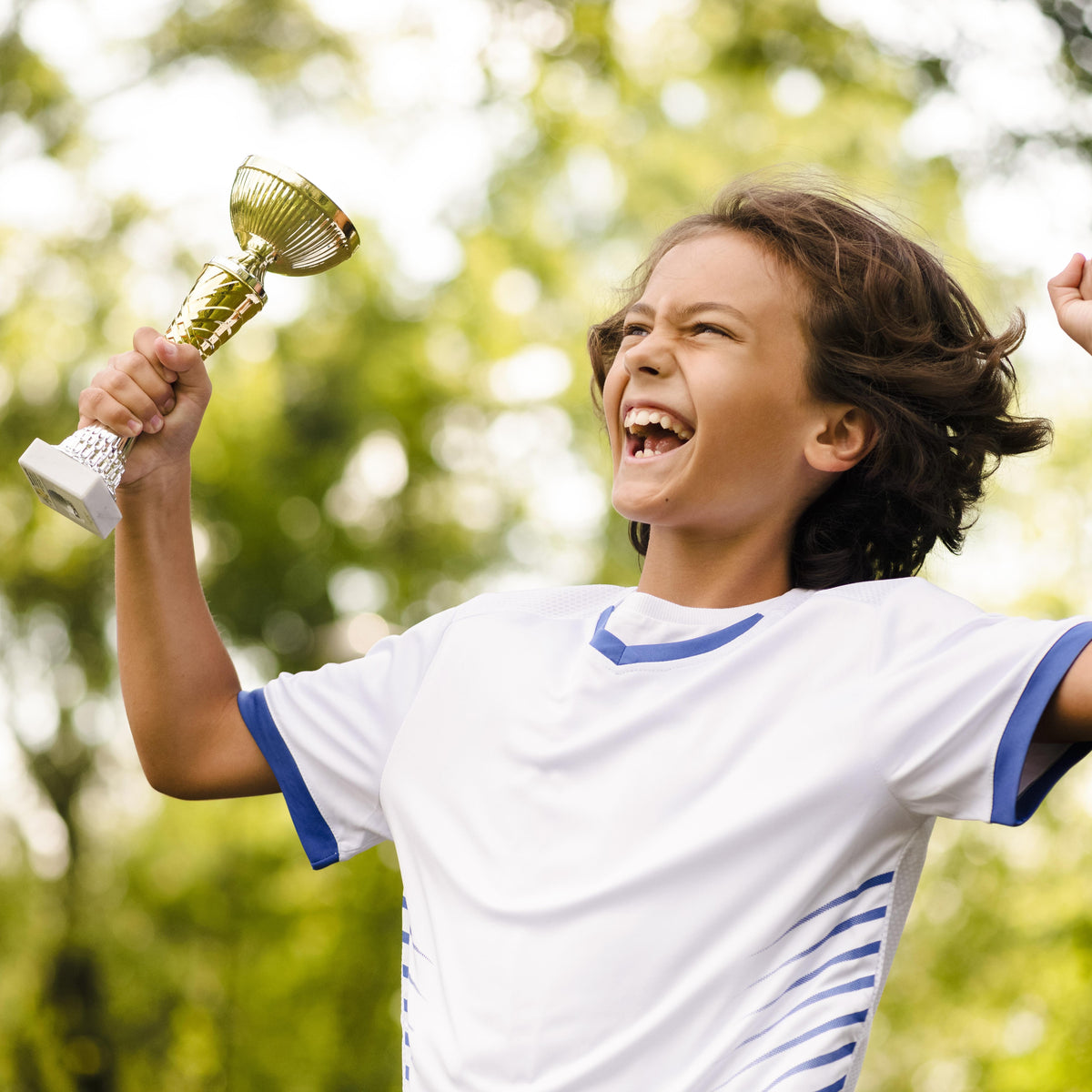 Child celebrating with a trophy outdoors