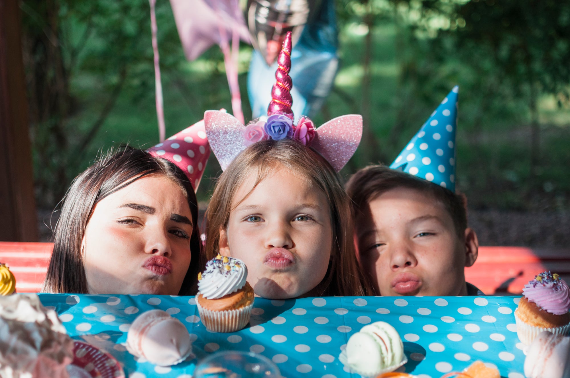 Children at a birthday party with cupcakes and colorful hats.