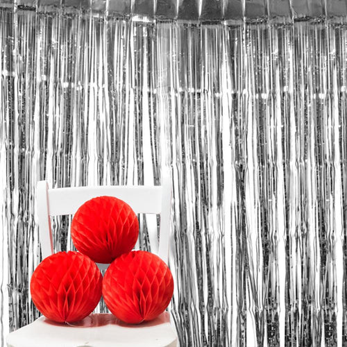 A metallic silver foil curtain with red pom poms