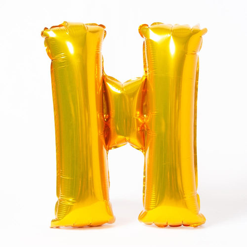 A shiny metallic gold letter "H" balloon