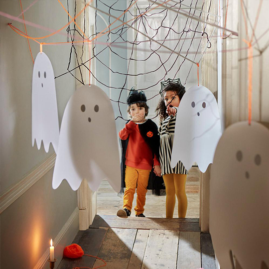 Ghost treasure hunt for kids, featuring cut-out ghosts handing in a corridor, with black spiders web