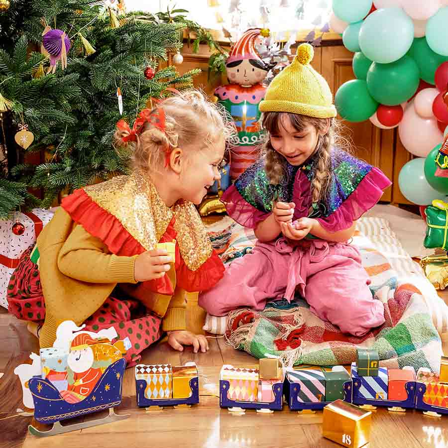 Two children enjoying Christmas sat amongst decorations