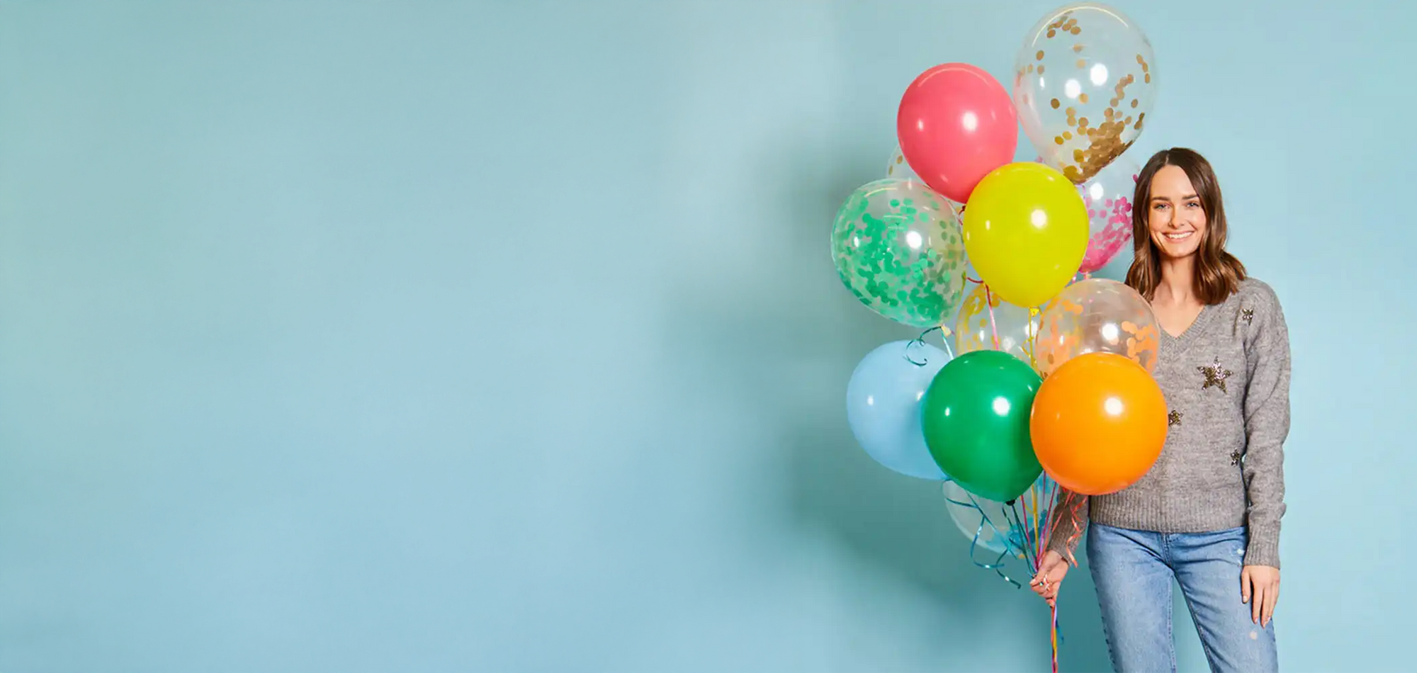 Woman holding colorful balloons against a light blue background