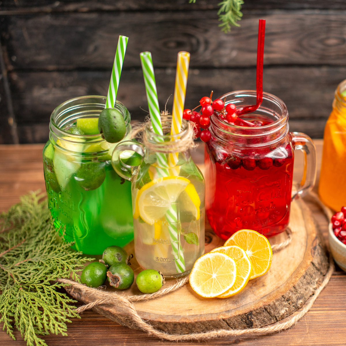 Three mason jars with colorful drinks and straws on a wooden tray.
