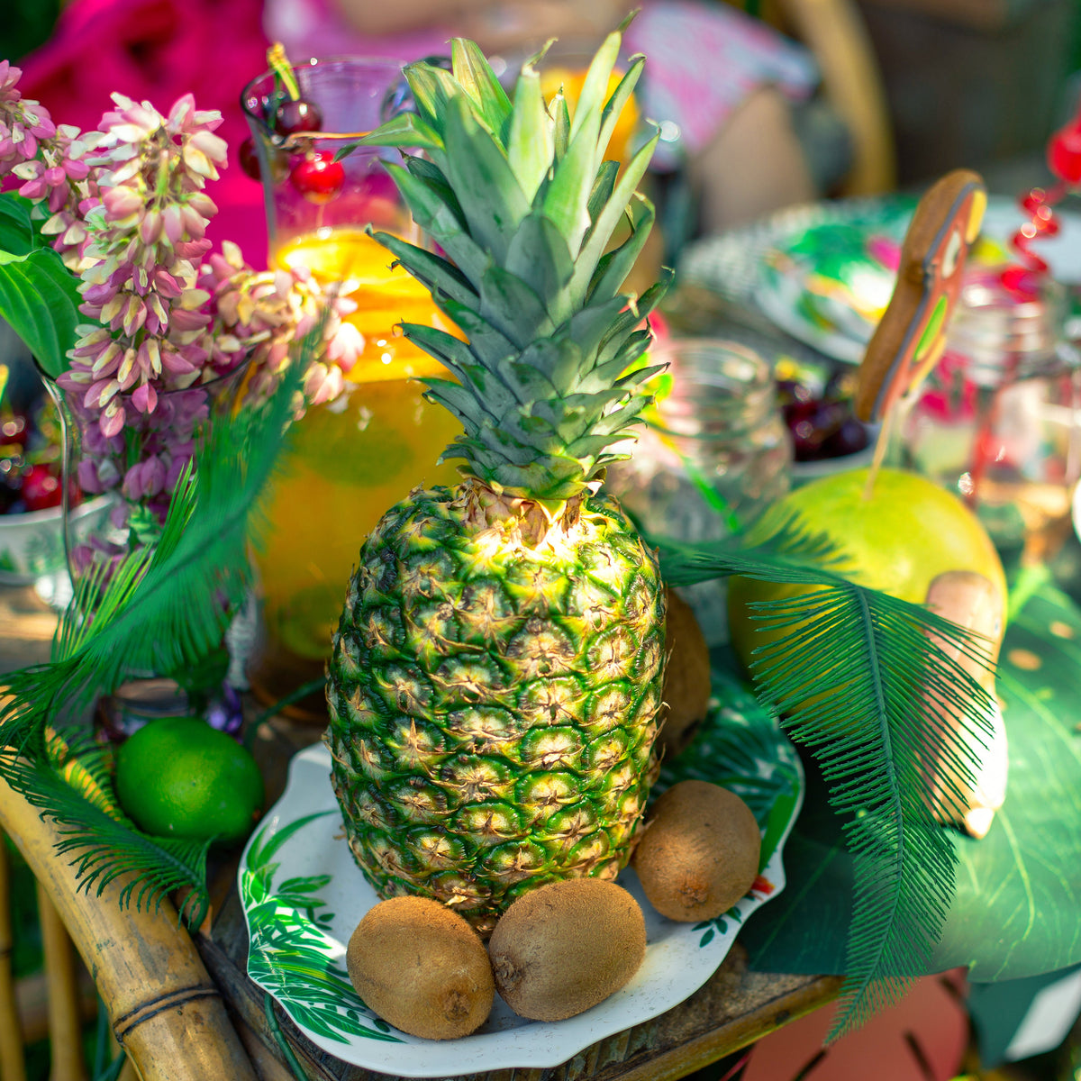 Decorative table setting with pineapple, kiwi, and tropical leaves on a colorful background