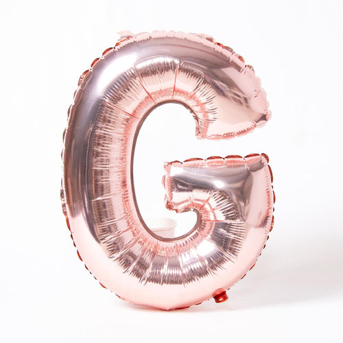 A rose gold foil balloon in the shape of the letter "G"