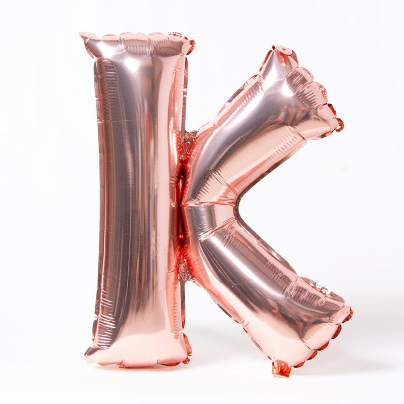 A rose gold foil balloon in the shape of the letter "K"