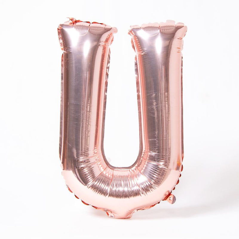 A rose gold foil balloon in the shape of the letter "U"