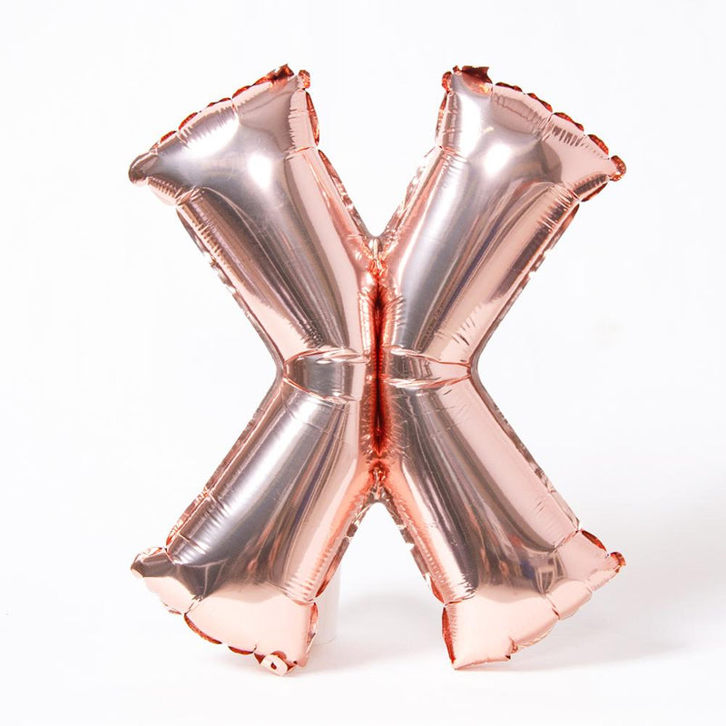 A rose gold foil balloon in the shape of the letter "X"