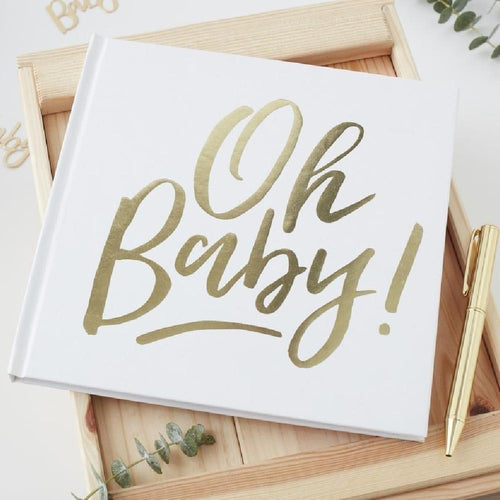 A baby shower guestbook with a white cover and gold foil writing saying "Oh Baby!"