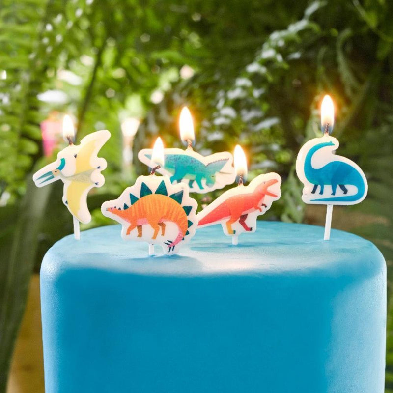 5 dinosaur-shaped party cake candles on top of a blue birthday cake
