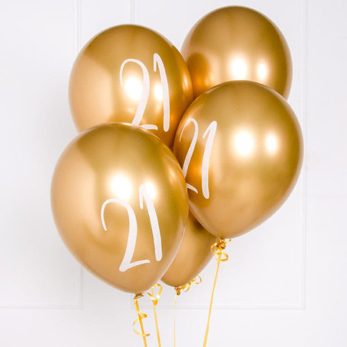 A bunch of metallic gold latex milestone party balloons with a number "21" on it