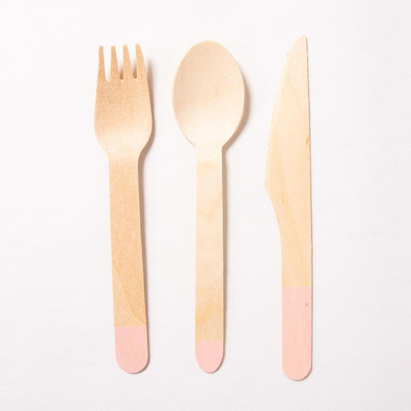 A wooden fork, spoon, and knife with a pink dipped colour on the handle